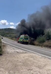 Ambulancia ardiendo con una gran columna de humo negro en una carretera