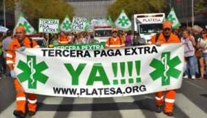 Manifestantes de PLATESA con uniformes naranjas portando una pancarta con el lema Tercera paga extra ya y banderas verdes.