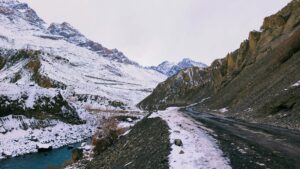 Carretera de montaña cubierta de nieve junto a un río en un paisaje invernal