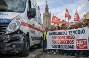 Trabajadores de Ambulancias Tenorio en Sevilla portando una pancarta con el texto sin concurso sin derechos sin seguridad, junto a una ambulancia deteriorada y banderas de UGT, con la Giralda al fondo
